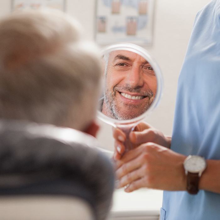 Man smiling at reflection in small mirror