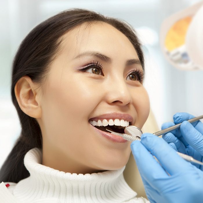 Woman smiling at dentist while they examine her teeth