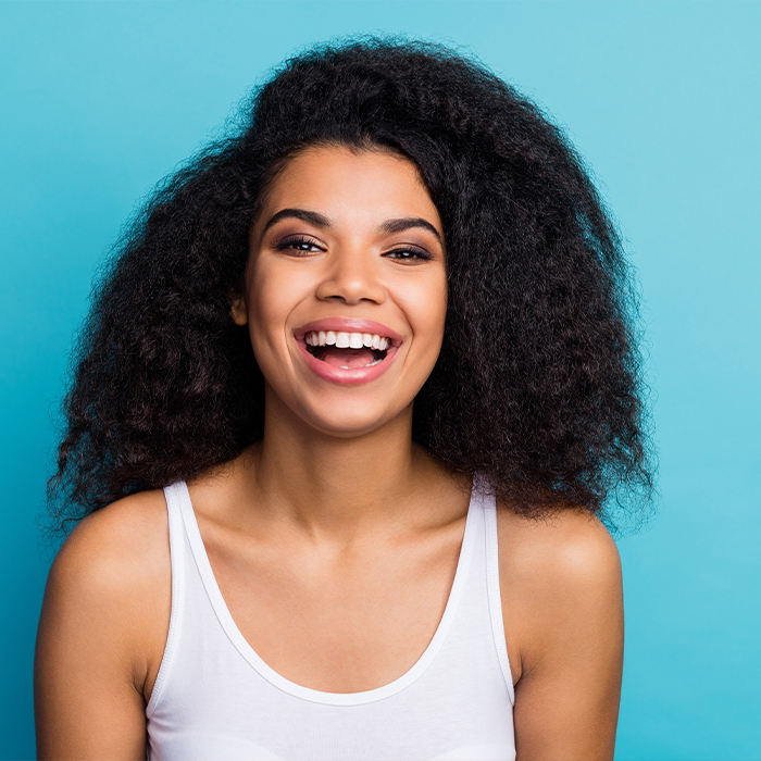 Woman smiling in front of turquoise background