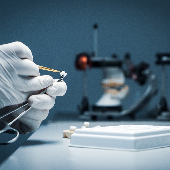 A lab worker making dental crowns