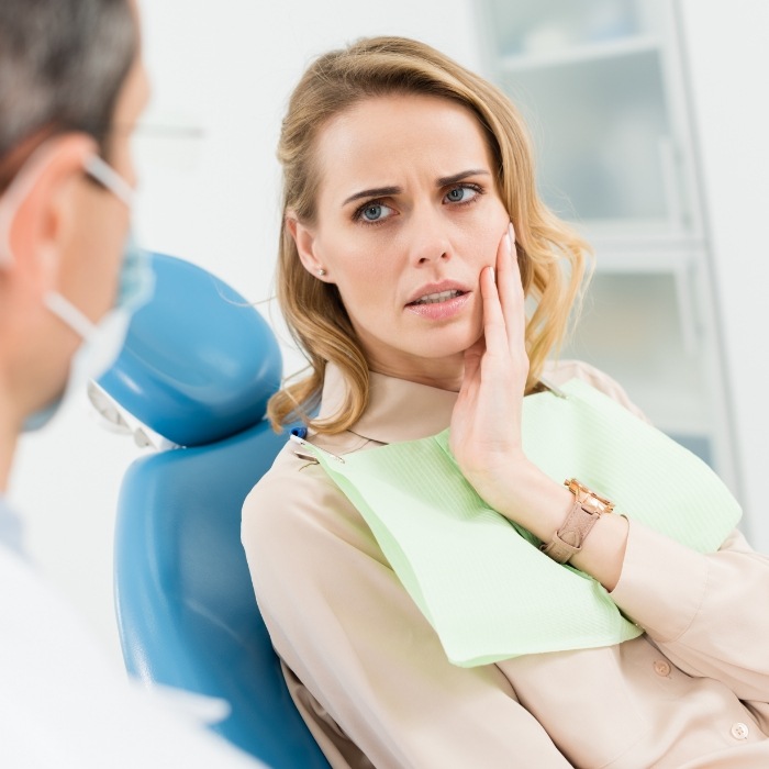 Woman holding her cheek in pain while visiting emergency dentist