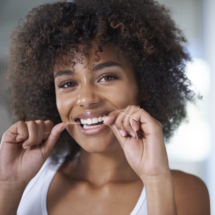 Woman smiling while flossing her teeth