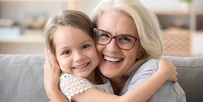 older woman smiling while holding granddaughter