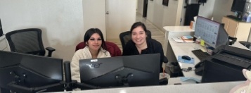 Two smiling dental team members at front desk