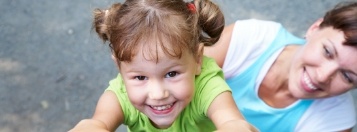 Child and mother smiling outdoors