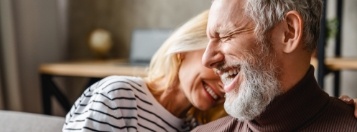 Senior man and woman laughing together in their living room