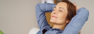 Relaxed woman laying on back with eyes closed and hands behind head
