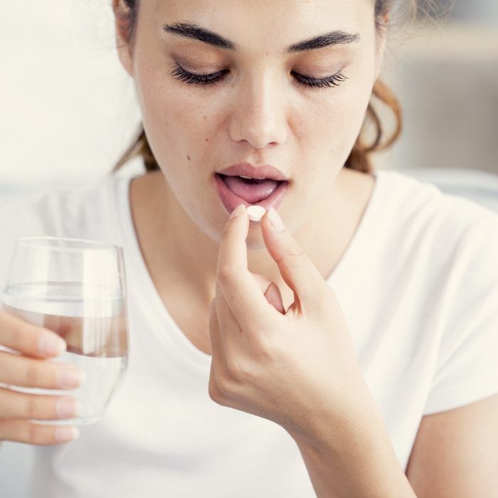 Woman taking pill with glass of water