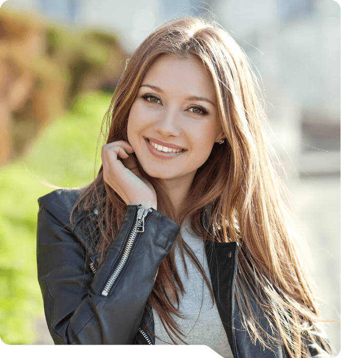Young woman in leather jacket smiling outdoors