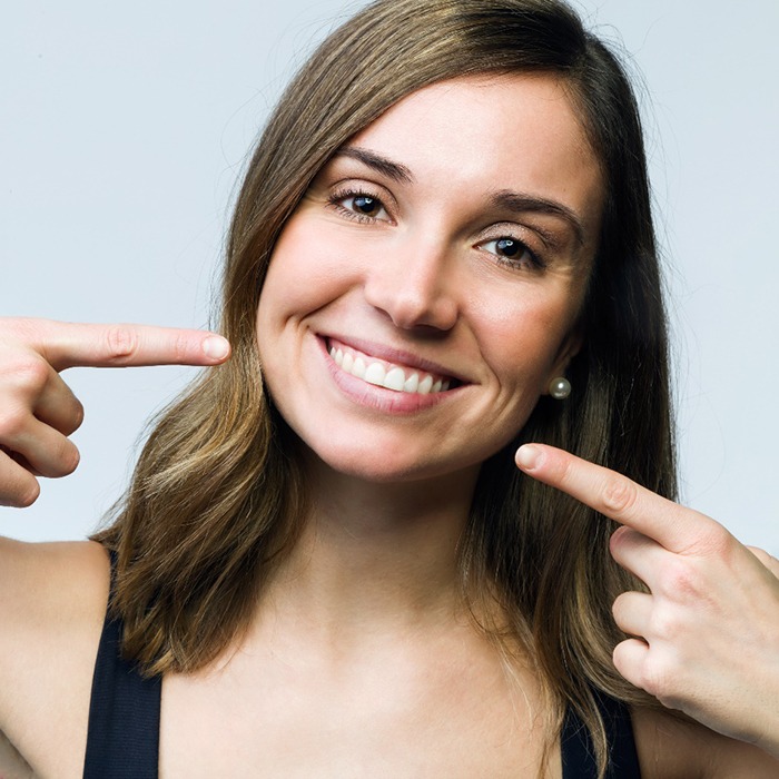 Woman smiling and pointing to her teeth