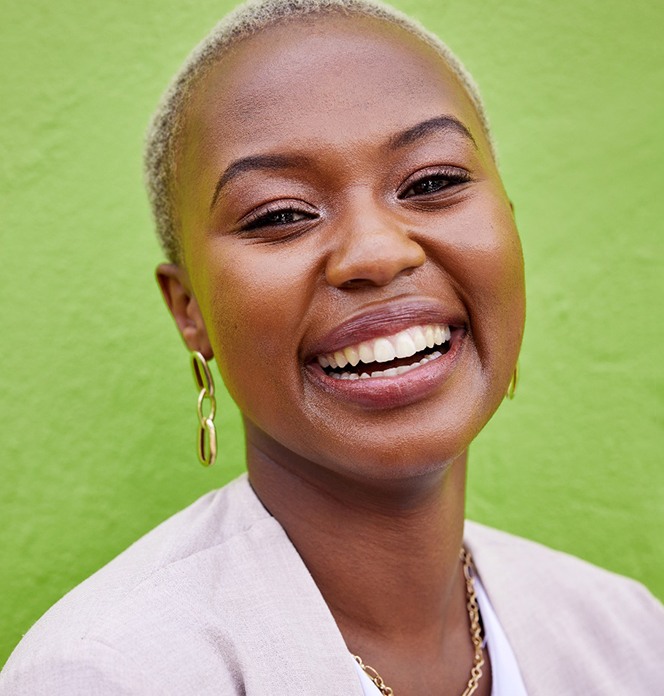 Woman in white shirt smiling in front of green wall